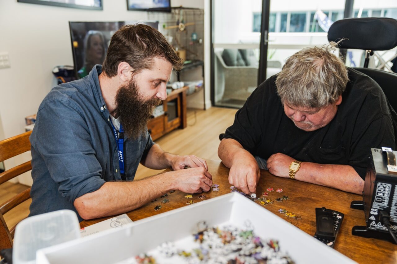 two men working on puzzles at a table.