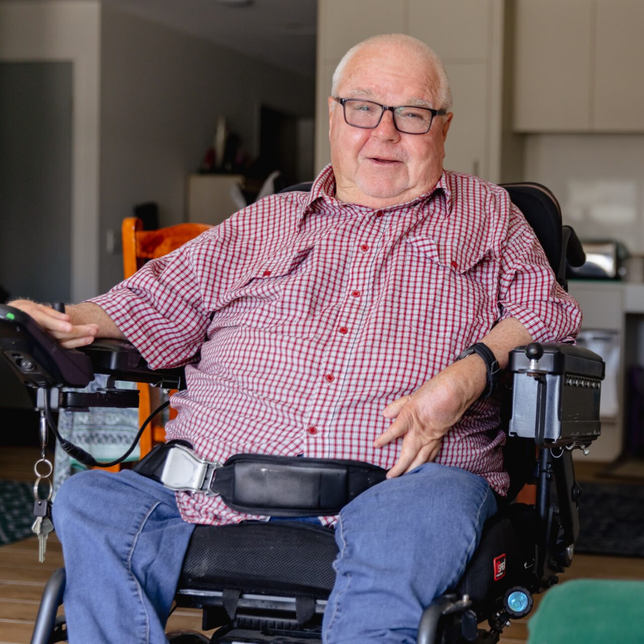 an older man sitting in a wheel chair holding a remote.