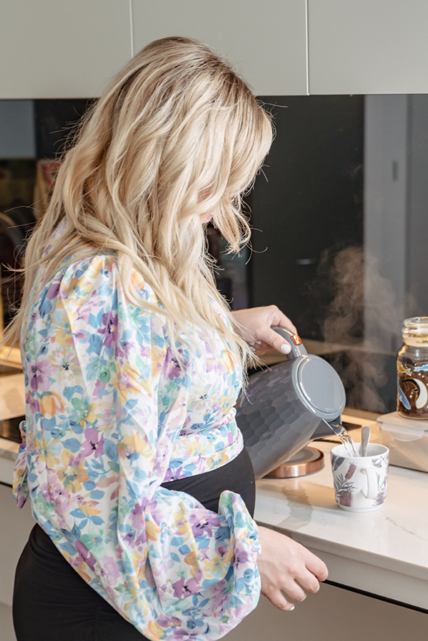 a pregnant woman preparing a cup of tea in the kitchen.