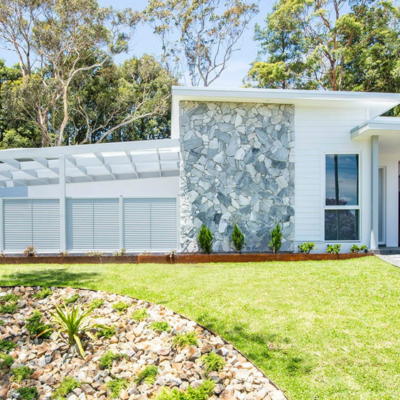 light coloured one story home with mixed rock façade and exterior landscaping